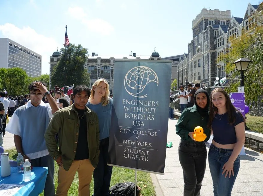 EWB-CCNY members at a campus event beside the chapter banner