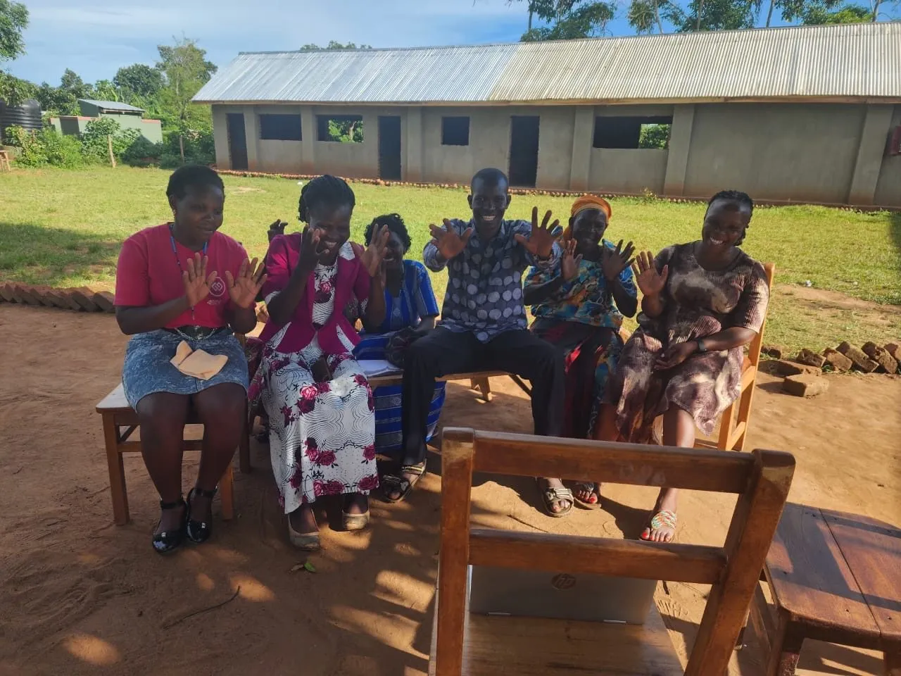 Community members seated outside a building in Kiswa, Uganda